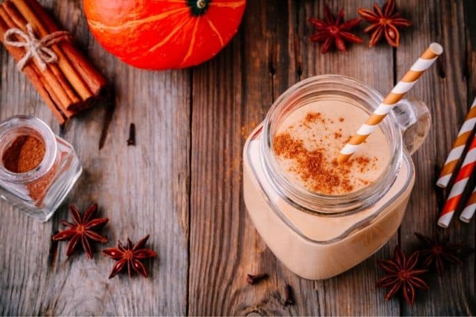 horizontal picture of pumpkin pie smoothie in jar-type glass with orange and white paper straw