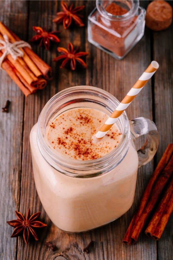 pumpkin pie smoothie in glass wood background with cinnamon sticks and star of anise