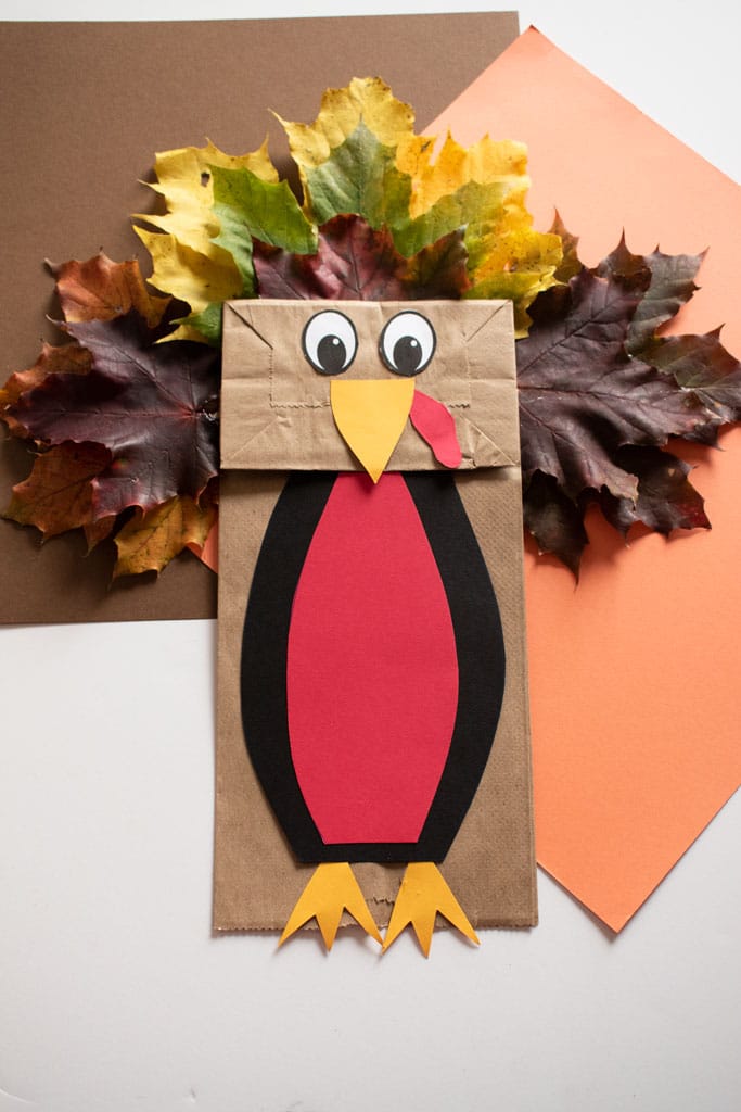 finished turkey paper bag puppet on brown, orange, and white background