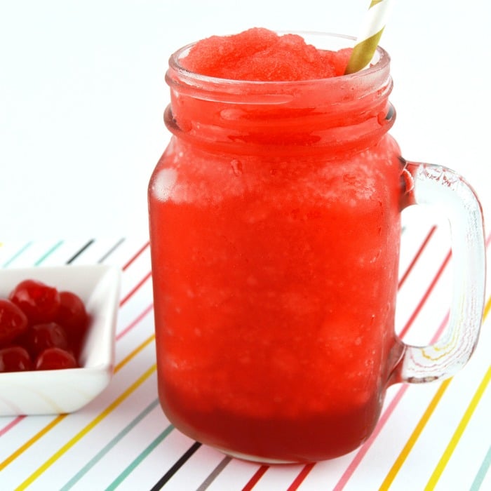 homemade cherry slushie in mason jar glass with maraschino cherries on the side