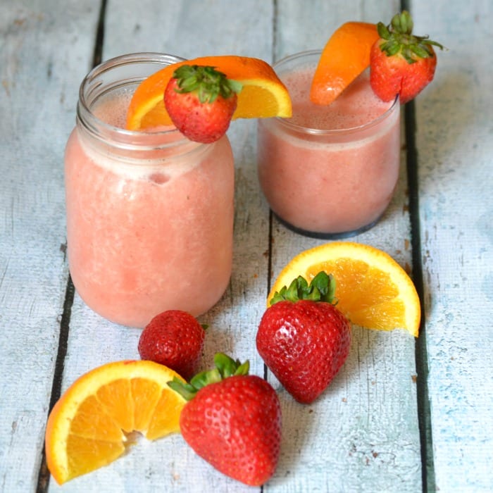 strawberry orange slushes garnished with orange slices and strawberries