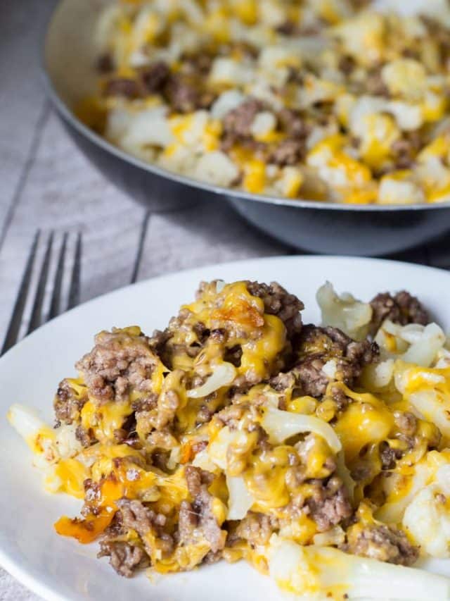 Ground beef and cauliflower meal on white plate with skillet in background
