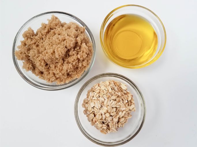 three small glass bowls containing brown sugar, olive oil, and oatmeal