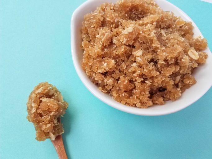 Easy brown sugar scrub in a white bowl with a wooden spoon in the lower left corner