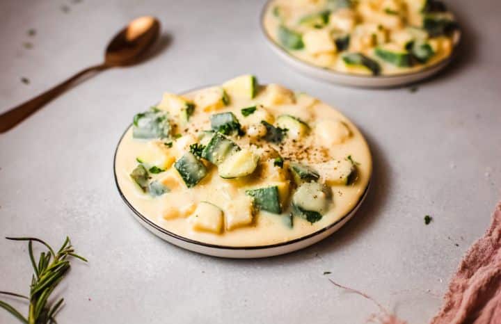 two dishes of zucchini mac and cheese on a light background