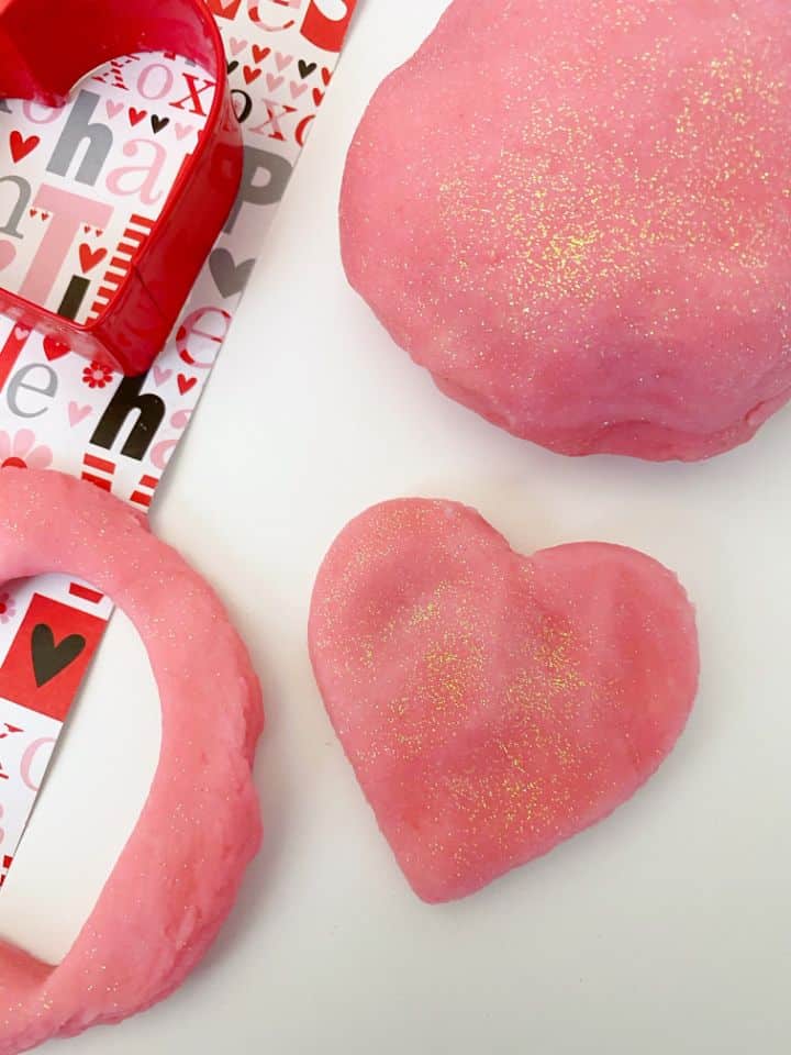 pink strawberry playdough on a white background with a heart shaped cookie cutter