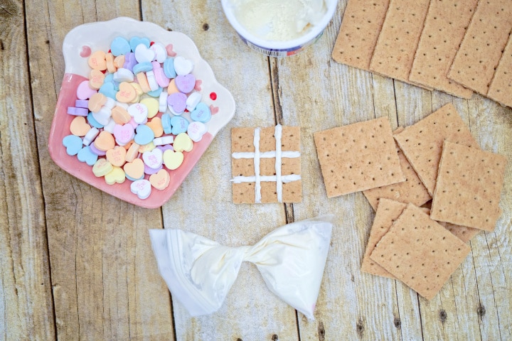 creating a tic tac toe board on the graham crackers using white icing