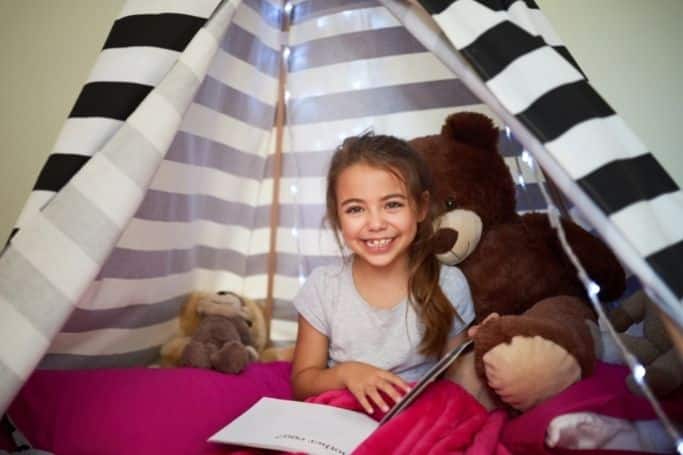 little girl in her reading nook with her teddy bear