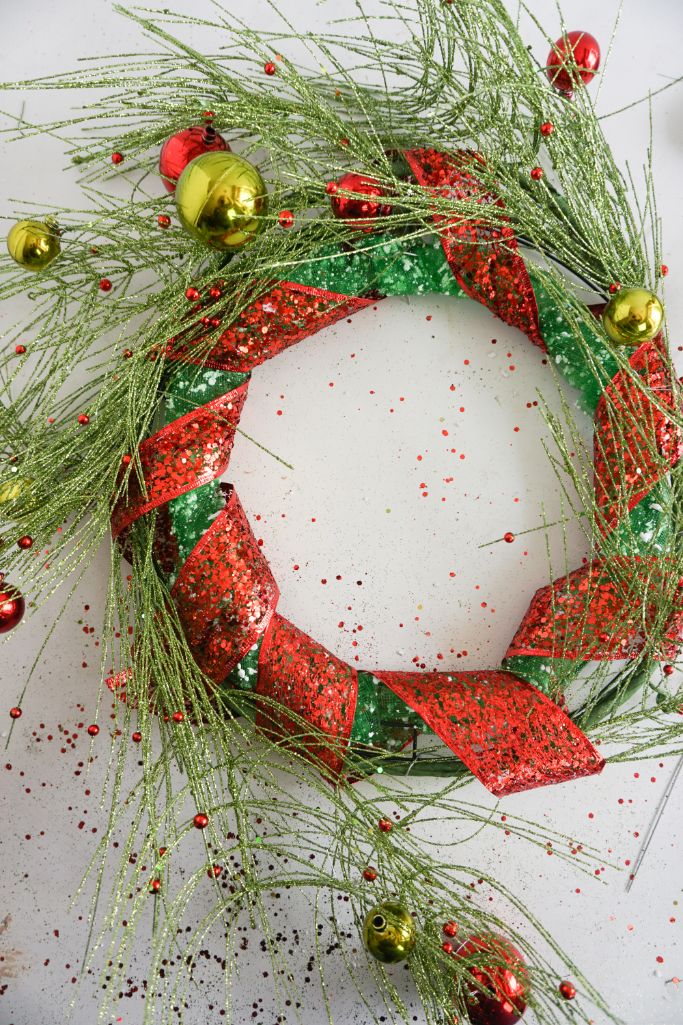 wreath form wrapped in pine garland and red ribbon