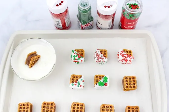 dipping the chocolate pretzel sandwiches in the candy melts and adding sprinkles