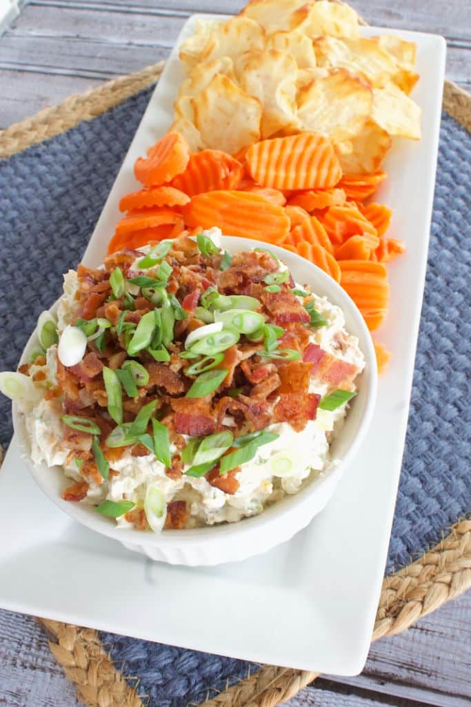 bacon pickle dip with carrots and crackers on a white serving platter