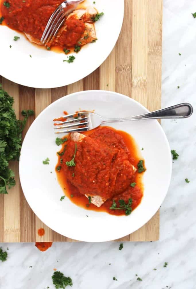 baked salmon with red pepper sauce on white plates