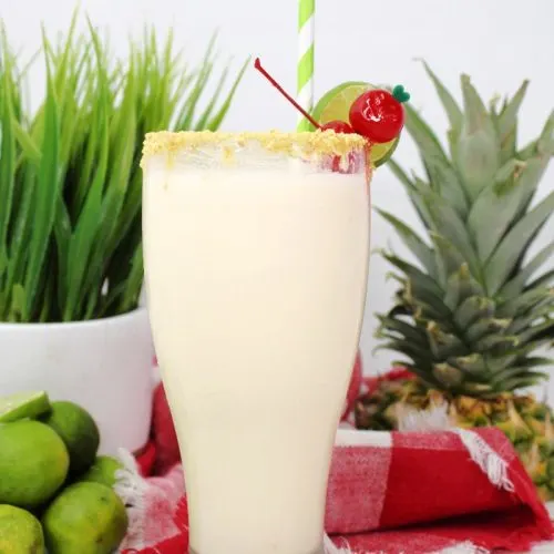 close shot of key lime colada in glass garnished with lime and cherries