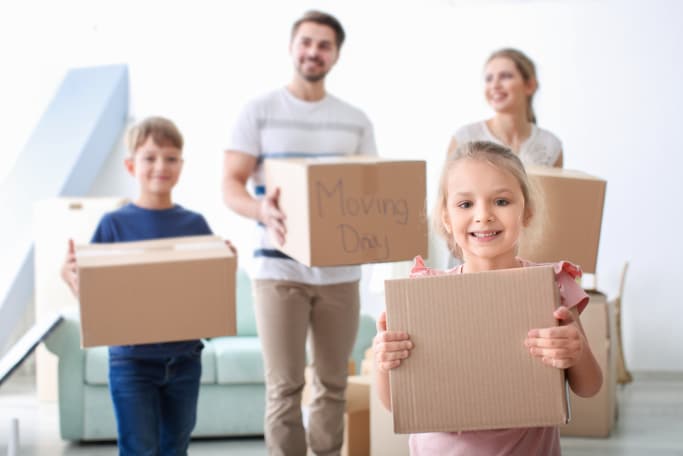 family of four holding boxes and preparing for a move
