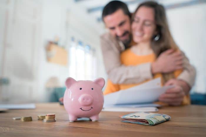 piggy bank in foreground with couple hugging in background