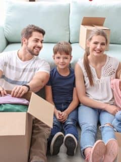 family sitting together in front of sofa surrounded by boxes