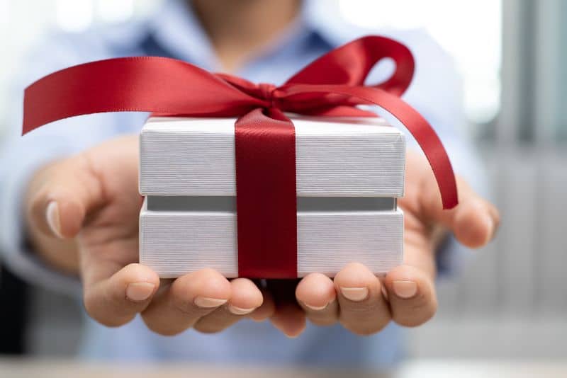 reaching a gift box to someone - white box and red ribbon