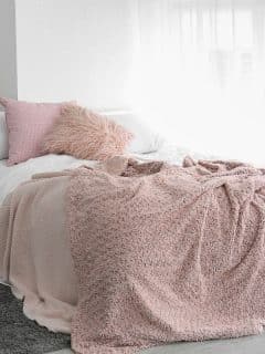 bedroom with white bedding and decor and pink accent pillows and blanket