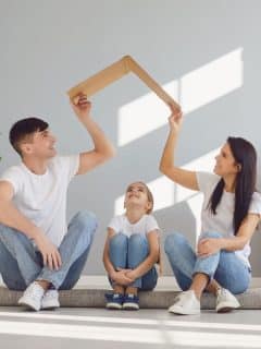 mom and dad holding cardboard roof over child