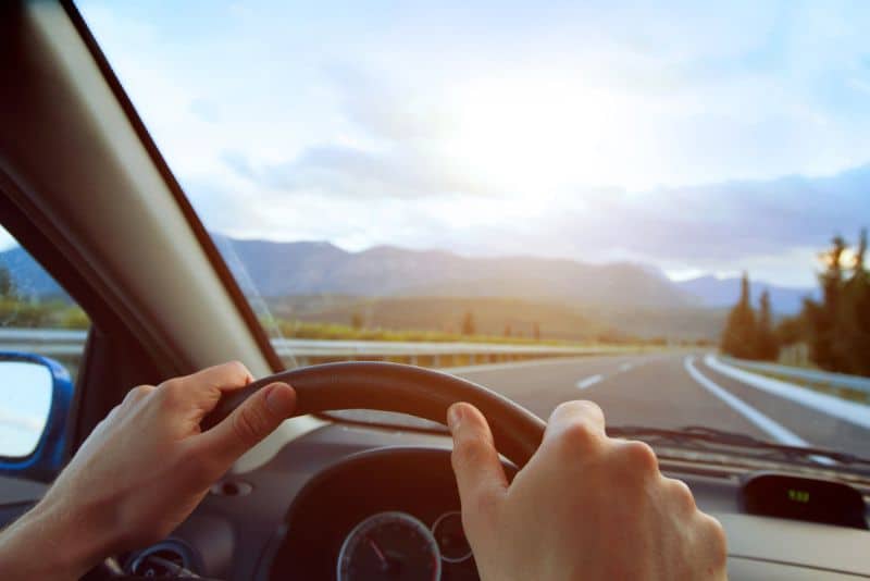 driving along an open highway, hands on steering wheel