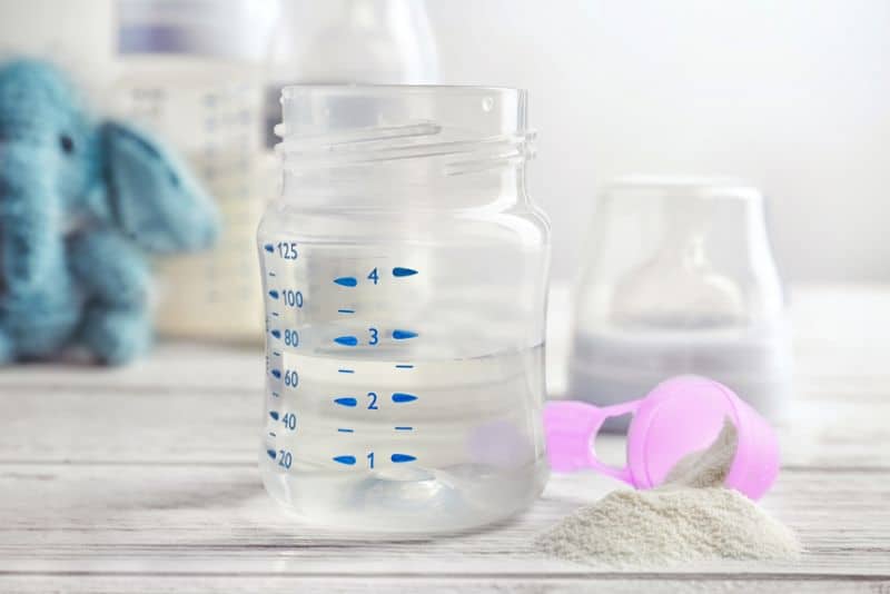 baby bottle with water and scoop of formula on the side