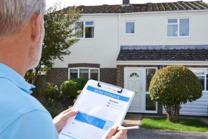 man looking at house holding paper for a work estimate