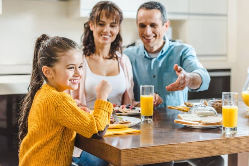 girl with her parents having breakfast