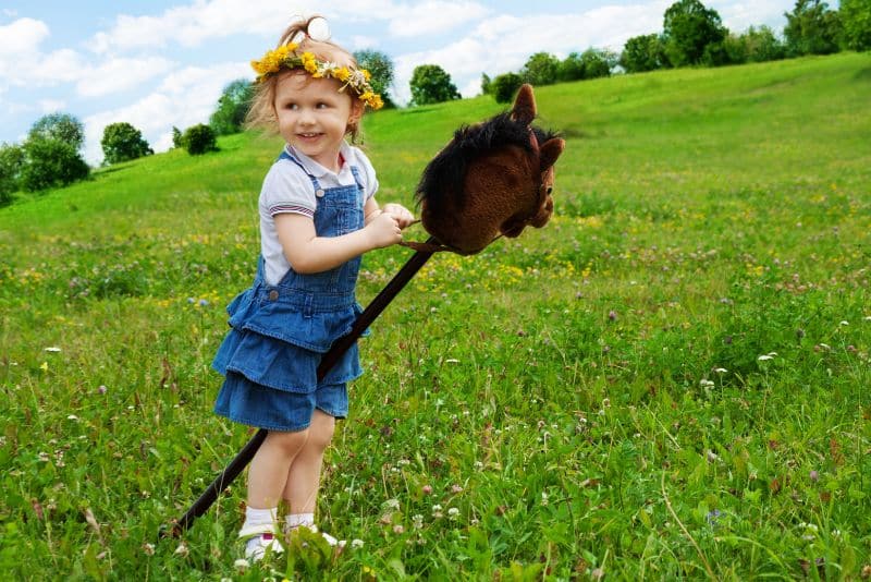 girl riding a stick horse