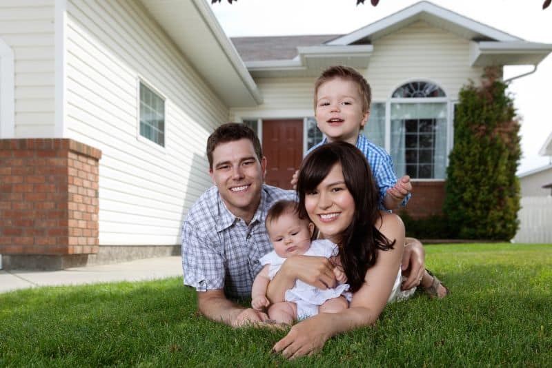 family of 4 in grass in front of house