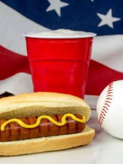 a hot dog, beer, and baseball in front of an american flag