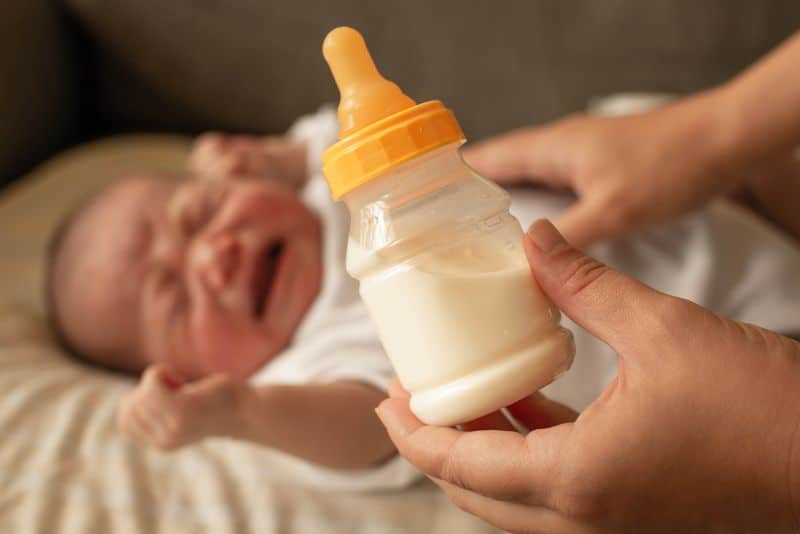 baby in background crying, bottle in foreground