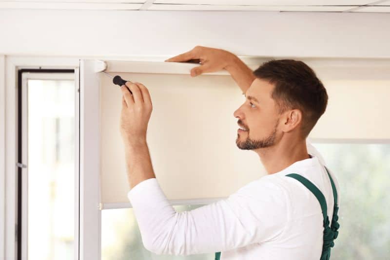 man installing window blinds