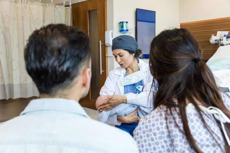 couple with doctor holding newborn