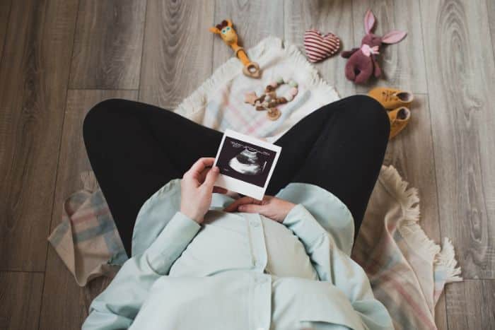 pregnant woman sitting holding ultrasound picture