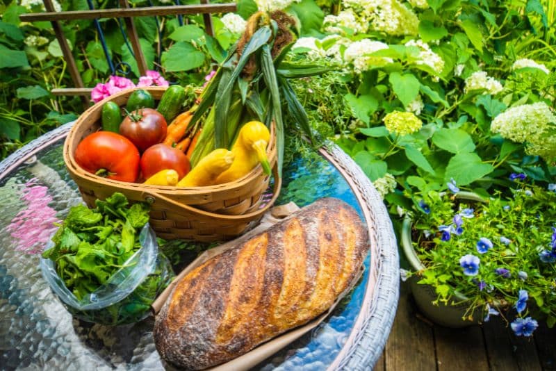 a loaf of fresh bread and fresh veggies from the garden