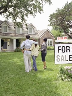 couple standing with realtor in yard