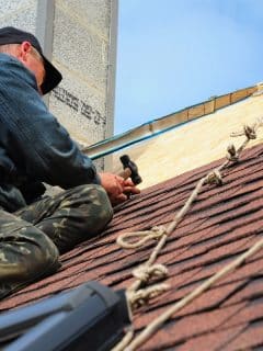 roofer nailing shingles to roof