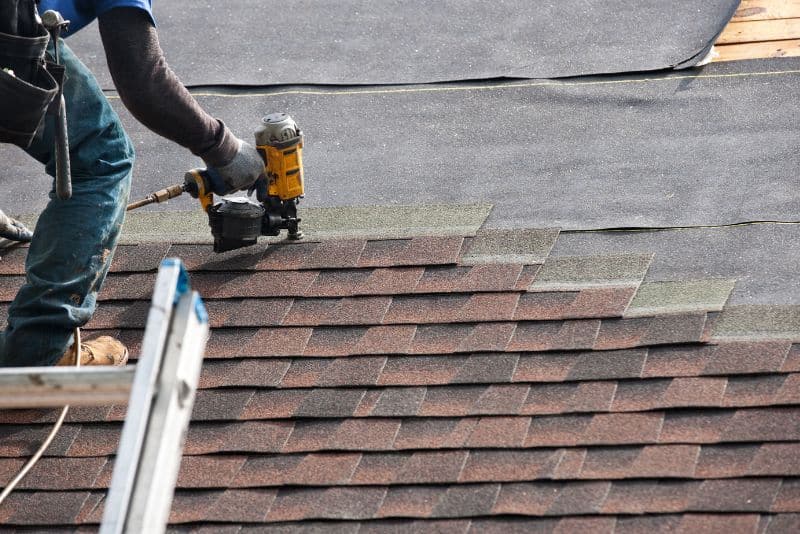 worker applying shingles to a roof