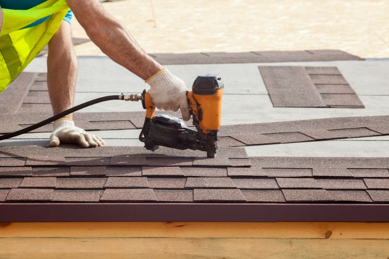 contractor installing shingles with nail gun