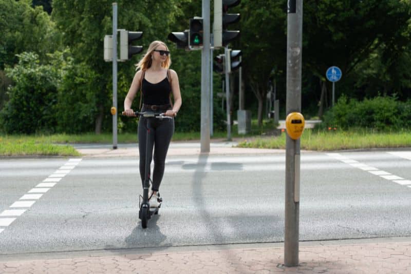 blonde woman on escooter crossing road
