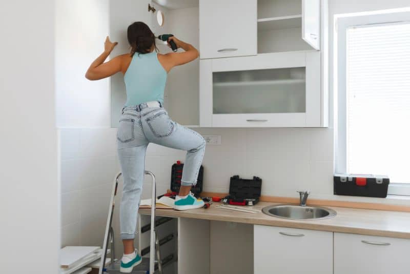 woman drilling into wall