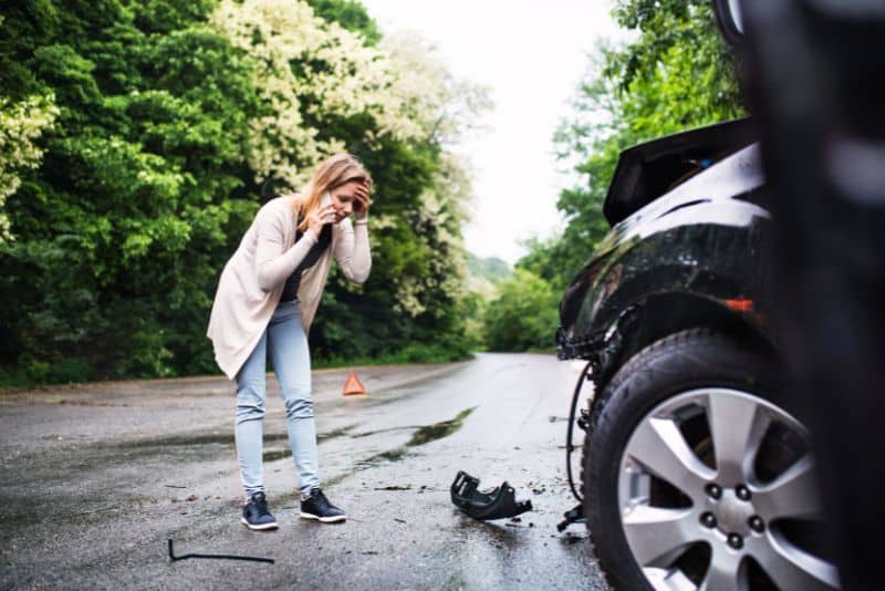 woman looking at debris in road while making a phone call