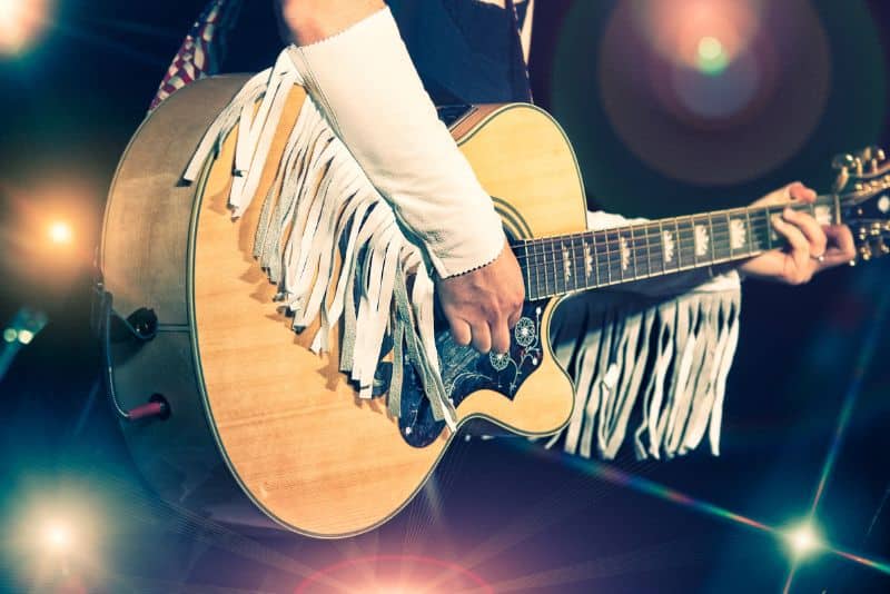 woman playing guitar and wearing fringe sleeves