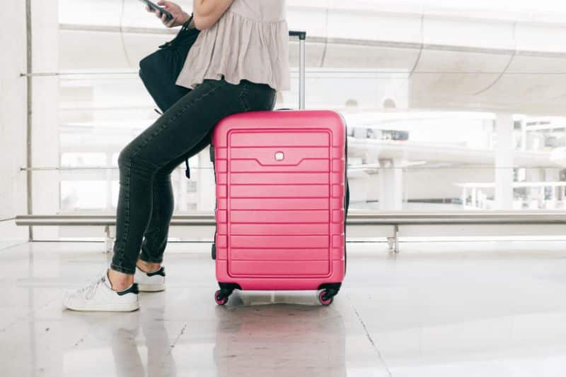 woman sitting on pink suitcase