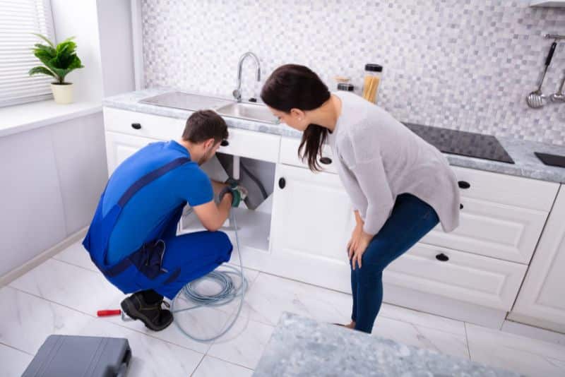 woman watching plumber clear a drain