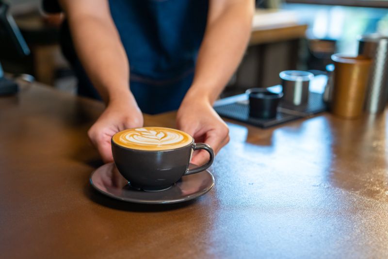 barista placing cup of coffee on counter