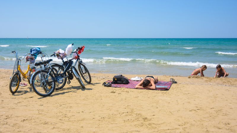 bicycles parked on beach while family relaxes