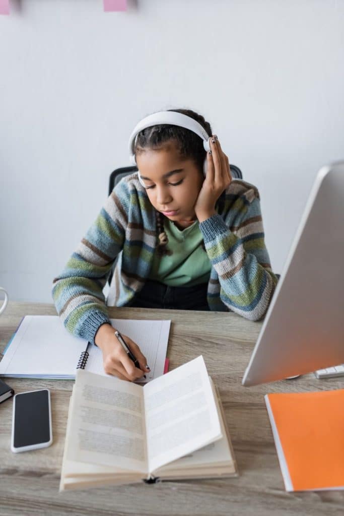 teenage girl studying while listening to headphones