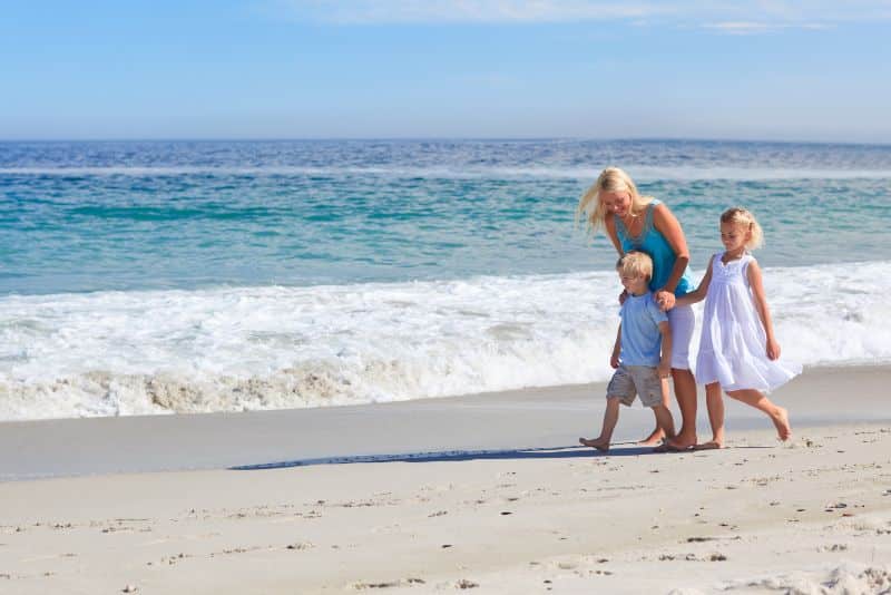 mother walking with her two children along the beach