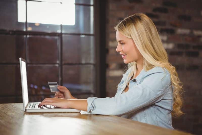 blonde woman using credit card for shopping online